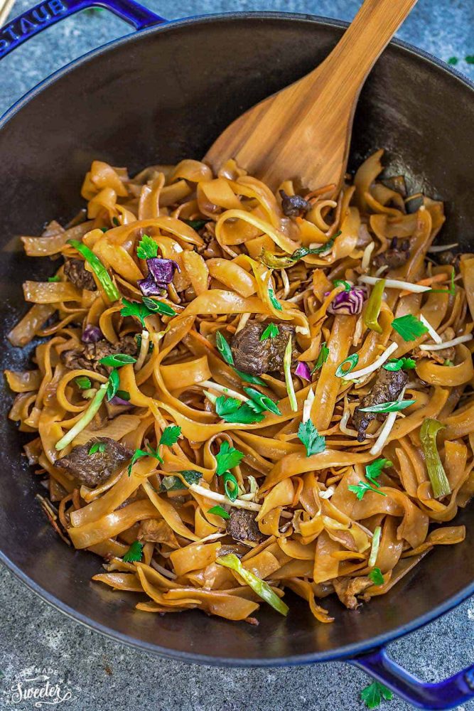 Delicious Fried Ho Fun Noodles in a blue dish with a wooden spoon.