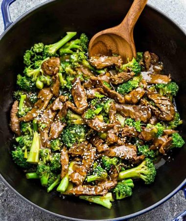 Beef and Broccoli and a wooden spoon in a black and blue skillet.