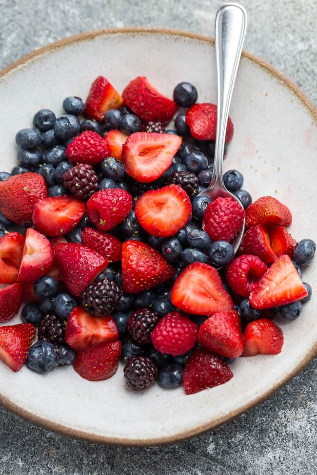 One bowl of berry fruit salad with silver spoon.