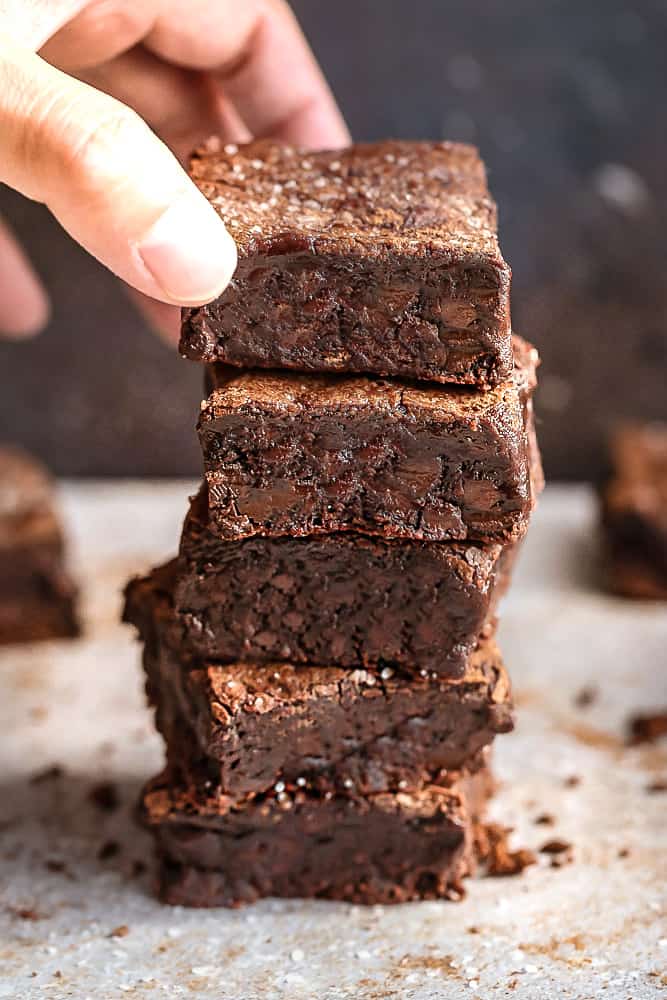 Five fudgy brownies stacked on top of each other on a table.