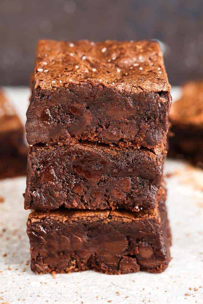 three fudgy brownies stacked on top of each other on a table.