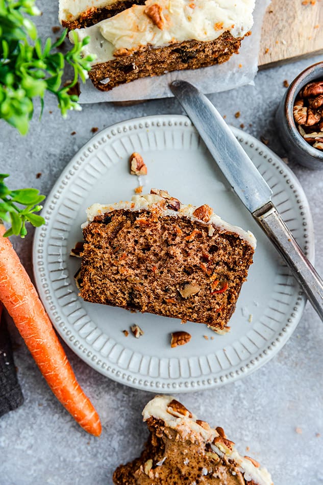 Top view of 1 slice of carrot loaf cake on a white plate with a knife