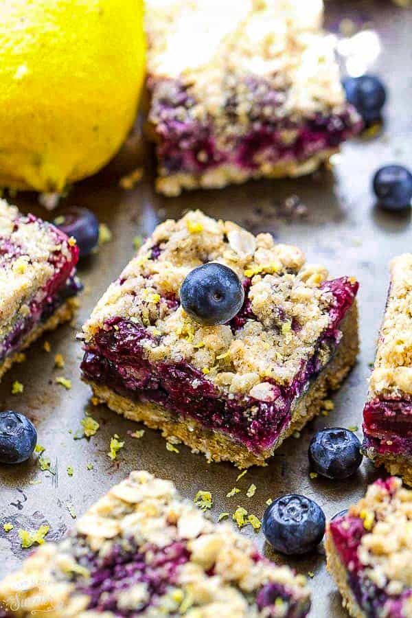 Front view of lemon blueberry crumble bars with fresh blueberries and lemon zest.