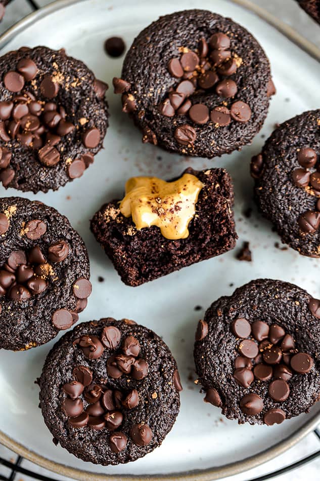 Close up view of one paleo chocolate muffin with a bite and a smear of nut butter
