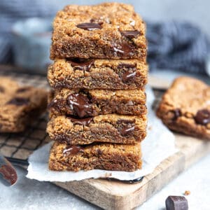 Side view of 5 stacked paleo chocolate chip cookie bars on a cutting board