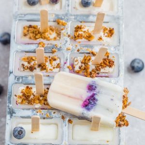 Blueberry popsicles in mold with granola and blueberries.