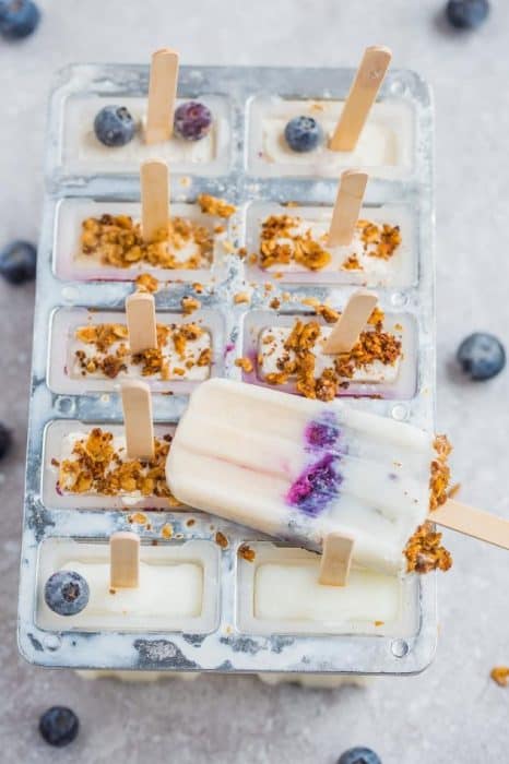 Blueberry popsicles in mold with granola and blueberries.