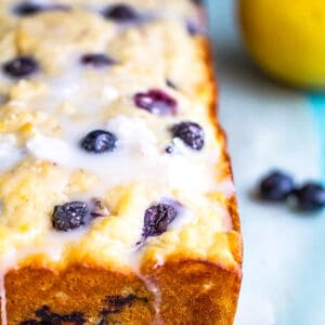 Side view of a loaf of lemon blueberry bread on parchment paper