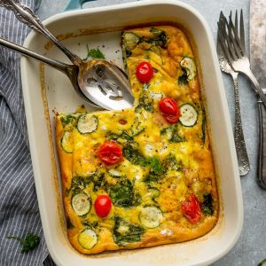 Top view of Whole30 Breakfast Casserole in a blue rectangle pan with a slice missing with serving spoons