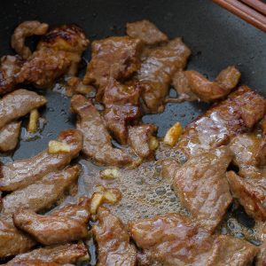 Stir fried flank steak strips cooking in pan