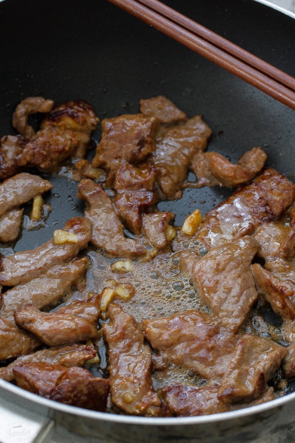 Searing marinated beef in a black skillet. 