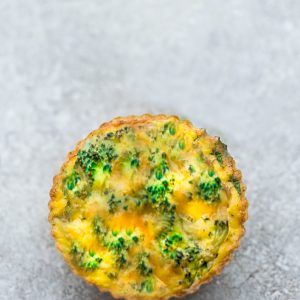 A Close-Up Shot of a Broccoli and Cheese Egg Muffin with a Gray Background