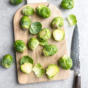 Top view of trimmed Brussels sprouts on a wooden cutting board with a knife