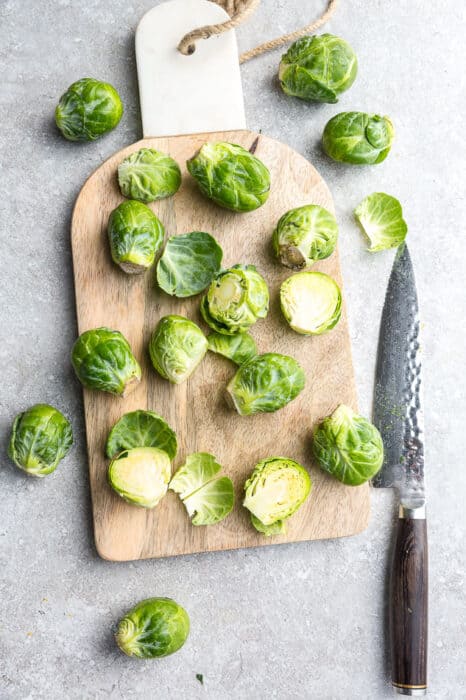 Top view of trimmed Brussels sprouts on a wooden cutting board with a knife