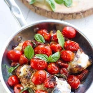 Overhead view of grilled chicken with blistered grape tomatoes, cheese and fresh basil in a bowl