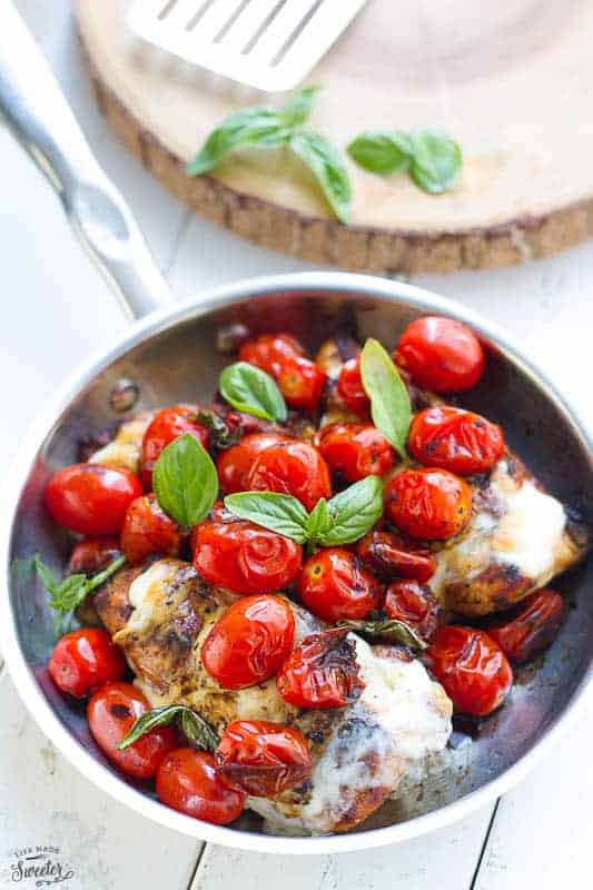 Overhead view of Caprese Chicken in a bowl with blistered tomatoes, cheese and fresh basil