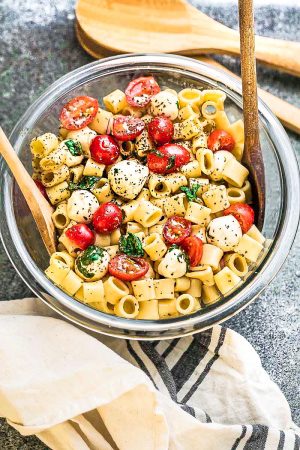 Caprese Pasta Salad - the perfect side dish to bring to summer potlucks, parties, Memorial Day / Fourth of July grillouts/barbecues. Best of all, it's so easy to make and easy to customize with your favorite toppings and homemade dressing. Perfect for Sunday meal prep and leftovers are delicious for school or work lunchboxes or lunchbowls.