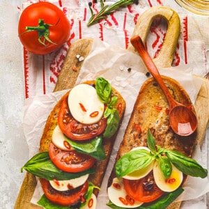 Two toasted sourdough slices topped with tomatoes, fresh mozzarella and basil