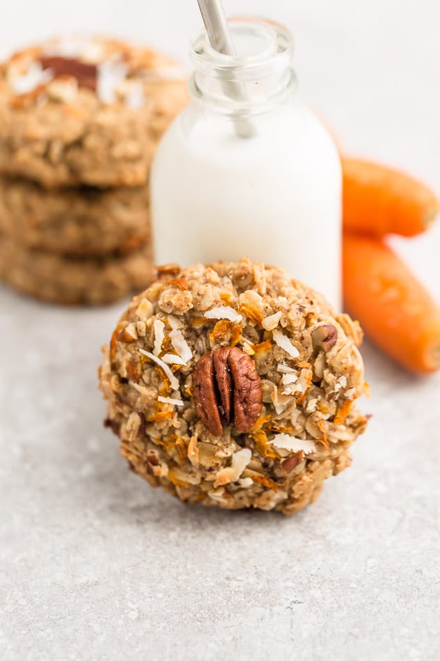 Side view of one healthy carrot cake cookies with a jug of milk behind the cookies