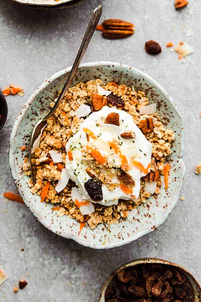 Overhead view of carrot cake granola in a bowl topped with yogurt