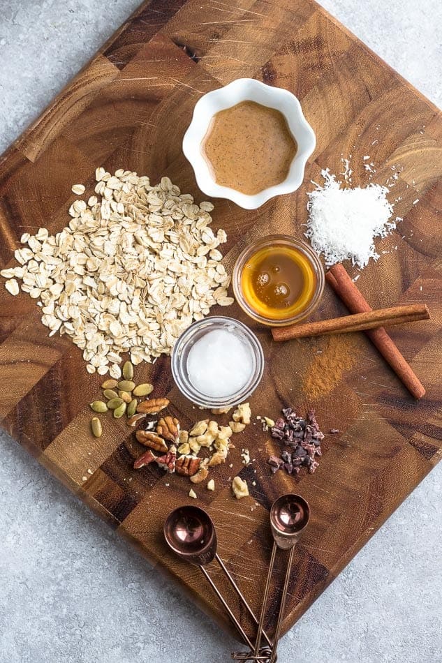 Cinnamon, maple syrup, old-fashioned oats and the rest of the carrot cake overnight oatmeal ingredients on a square cutting board
