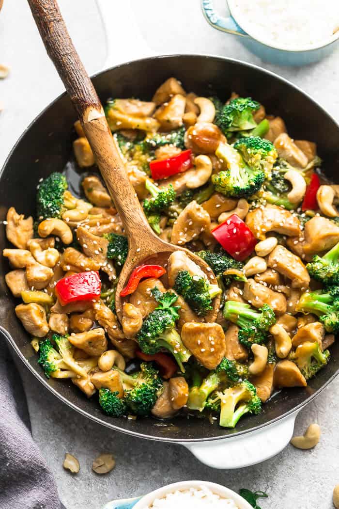 Easy Cashew Chicken recipe in a cooking skillet and a wooden spoon.