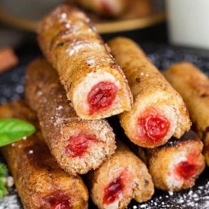 A stack of cherry cheesecake French Toast roll-ups on a plate