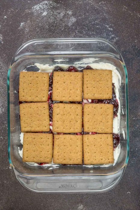 Cheesecake, cherries, and graham crackers layered in a square baking dish