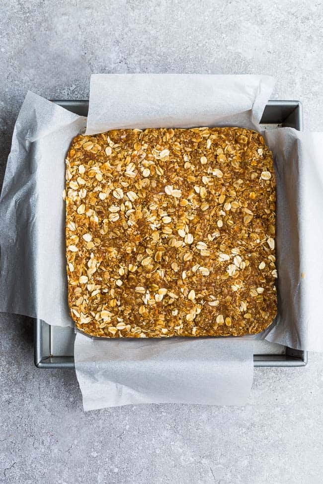 Overhead view of a parchment-lined square pan of Homemade Granola Bars 