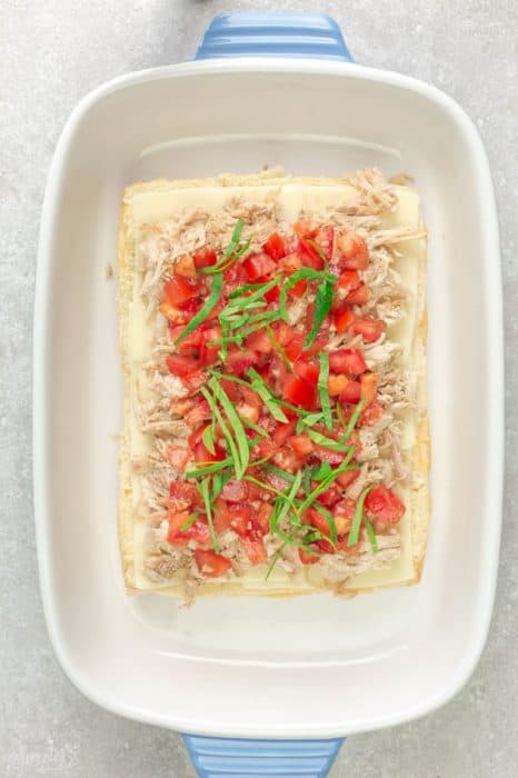 Top view of a dozen open-faced Italian Chicken Bruschetta Sliders topped with diced tomatoes and basil