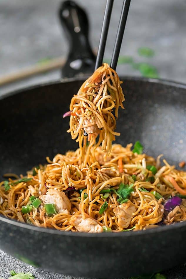 Side view of Chicken Chow Mein in a wok with chopsticks