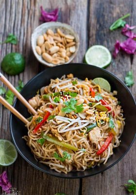Top view of chicken pad thai in a bowl with chopsticks
