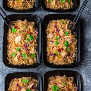 Top view of traditional pad thai in 4 black meal prep containers
