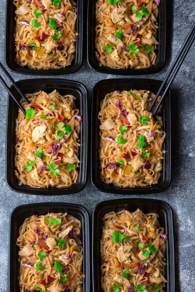 Six black meal prepping bowls with an Authentic Chicken Pad Thai recipe on a grey counter.
