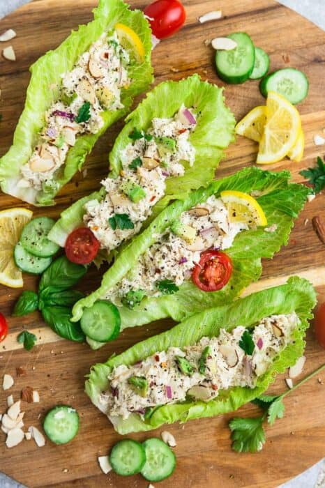 Top view of 4 chicken salad lettuce wraps on a white plate on a wooden board
