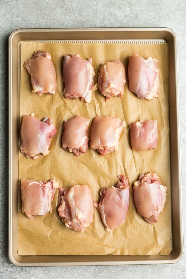 Top view of raw chicken thighs on a baking sheet for Chicken Shawarma recipe