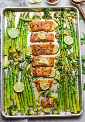 Top view of a sheet pan with Chili Lime Salmon fillets with asparagus and broccoli and lime slices