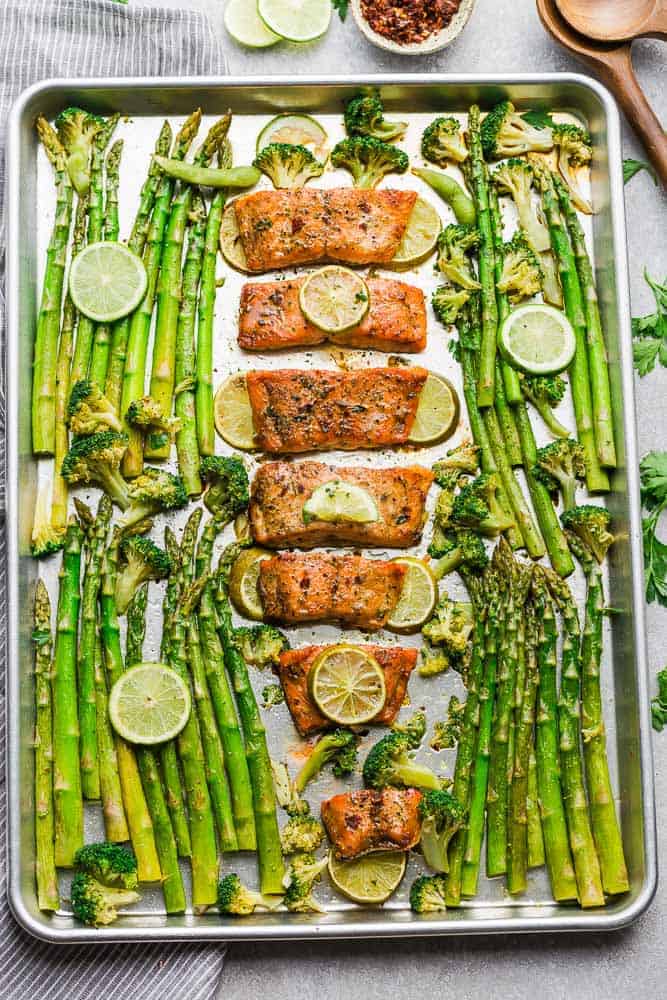 Top view of a sheet pan with Chili Lime Salmon fillets, asparagus and broccoli with lime slices