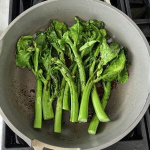 A bunch of fresh Chinese broccoli (Gai Lan) in a grey pan with coconut aminos
