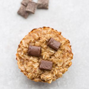 A single peanut butter baked oatmeal cup on a countertop with three chocolate chunks pressed into the top