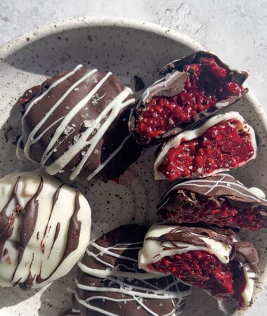 Five chocolate raspberry bites with two cut into halves in a white bowl