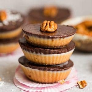 A stack of homemade nut butter chocolate cups topped with a pecan