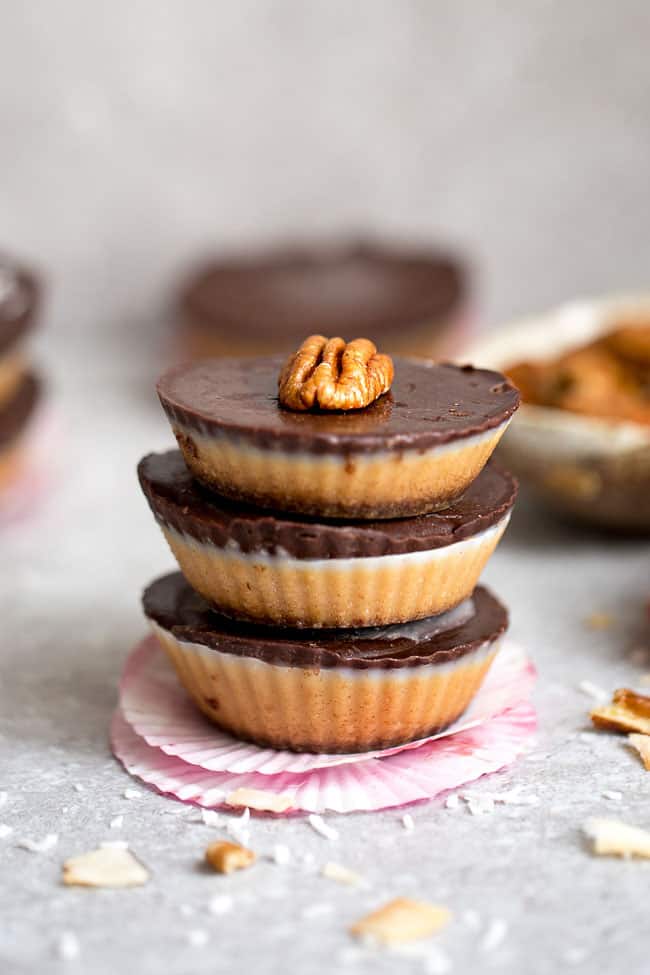 A stack of homemade nut butter cups topped with chocolate and pecan