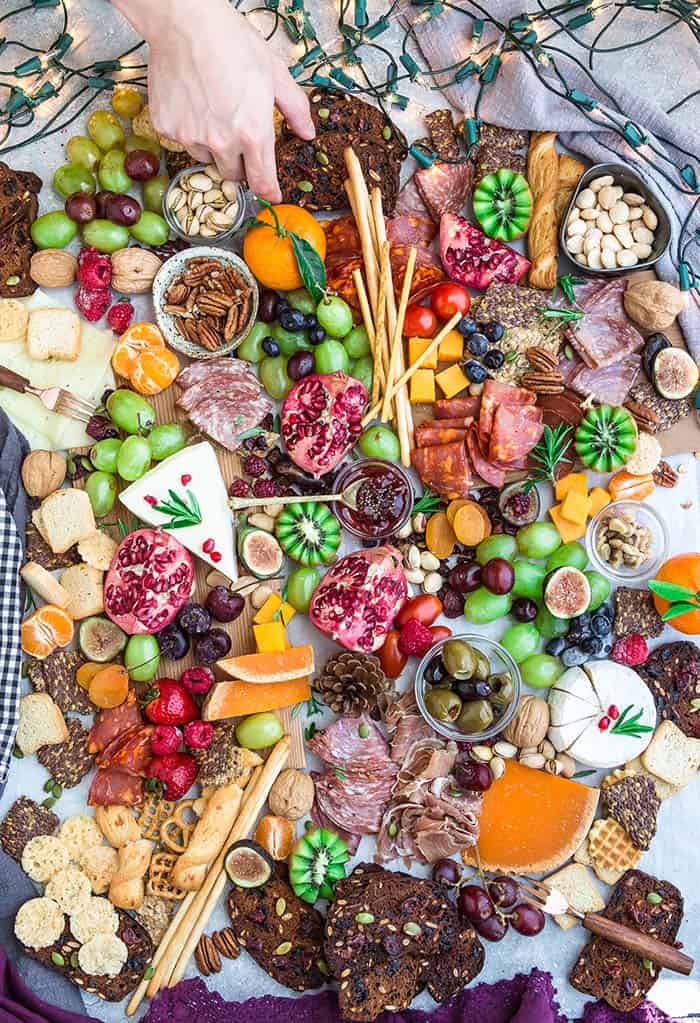 Top view of a variety of crackers, fruits, nuts, meats and cheeses on a holiday charcuterie board