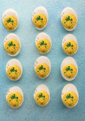 Top view of 12 Classic Deviled Eggs on a blue board