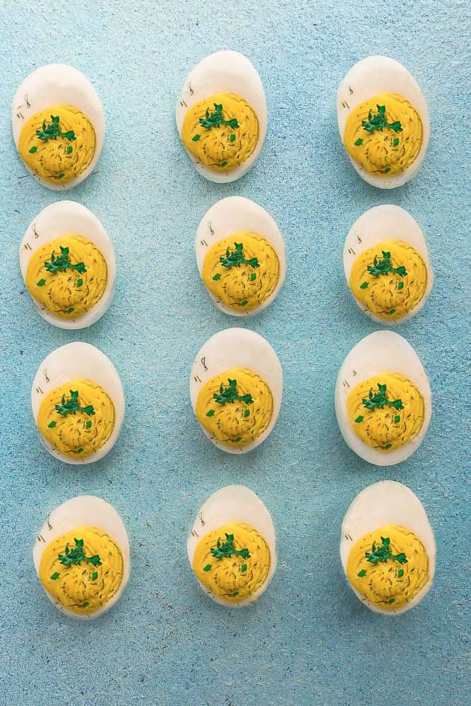 Top view of 12 Classic Deviled Eggs on a blue board