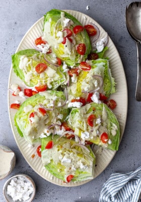 Six wedge salad portions on a white oval serving platter