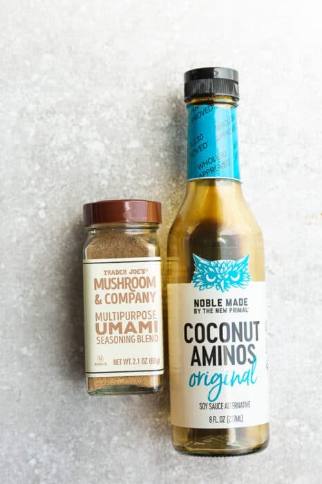 A bottle of Trader Joe's coconut aminos and Trader Joe's multipurpose mushroom umami seasoning on a countertop