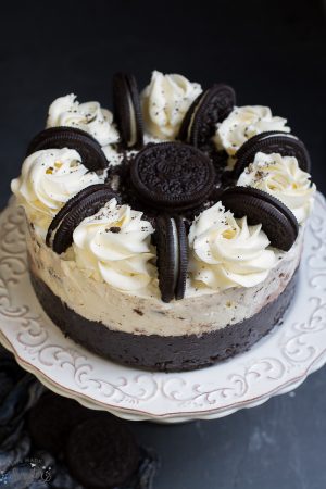 Delicious Cookies and Cream Oreo Ice Cream Cake topped with whole oreos on a white cake plate.