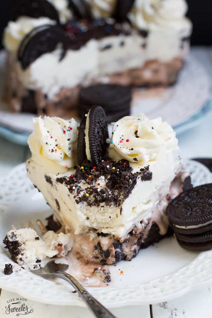 Slice of cookies and cream ice cream cake being served on fork and white plate.